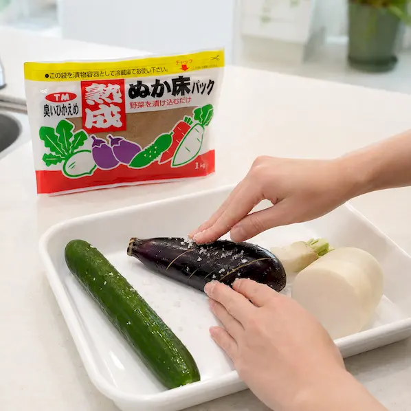 きゅうり、紫色のなす、大根を清潔なまな板の上で軽く塩もみしているイメージ