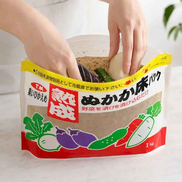 きゅうり、紫色のなす、大根をぬか床の中へ沈めているイメージ