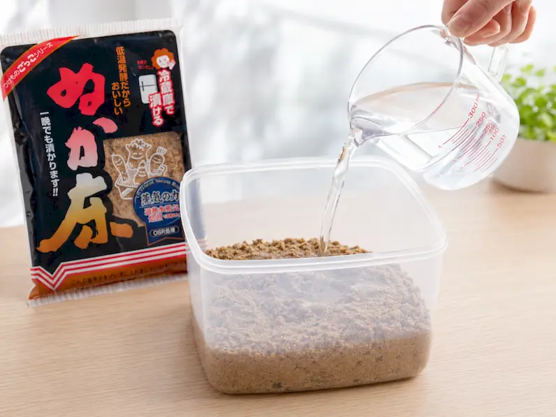 計量カップから冷まし水300ccをぬか床に注いでいる工程