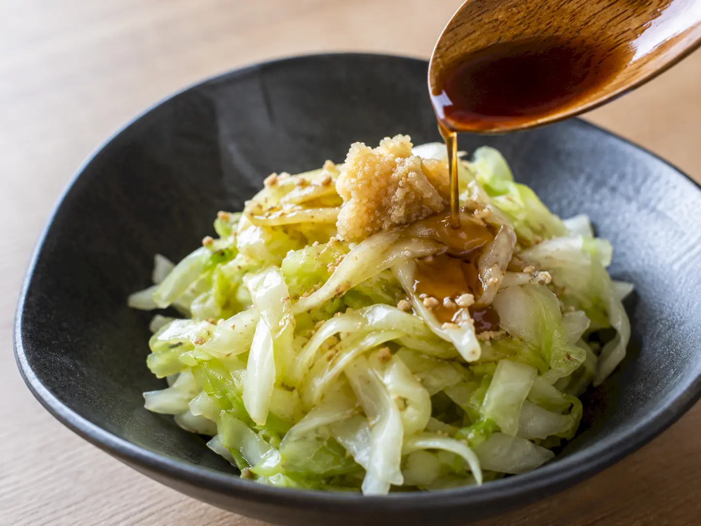 ぬか漬けキャベツに木製スプーンでめんつゆをかける工程