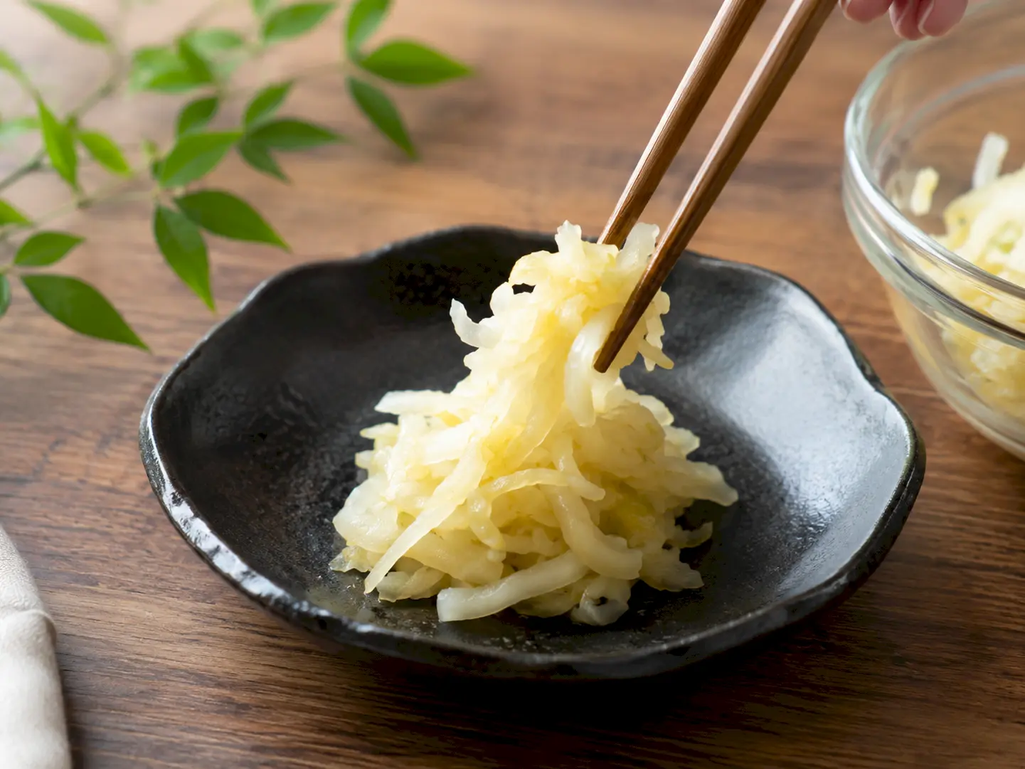 千切りにしたぬか漬けキャベツを黒い和食器に盛る工程
