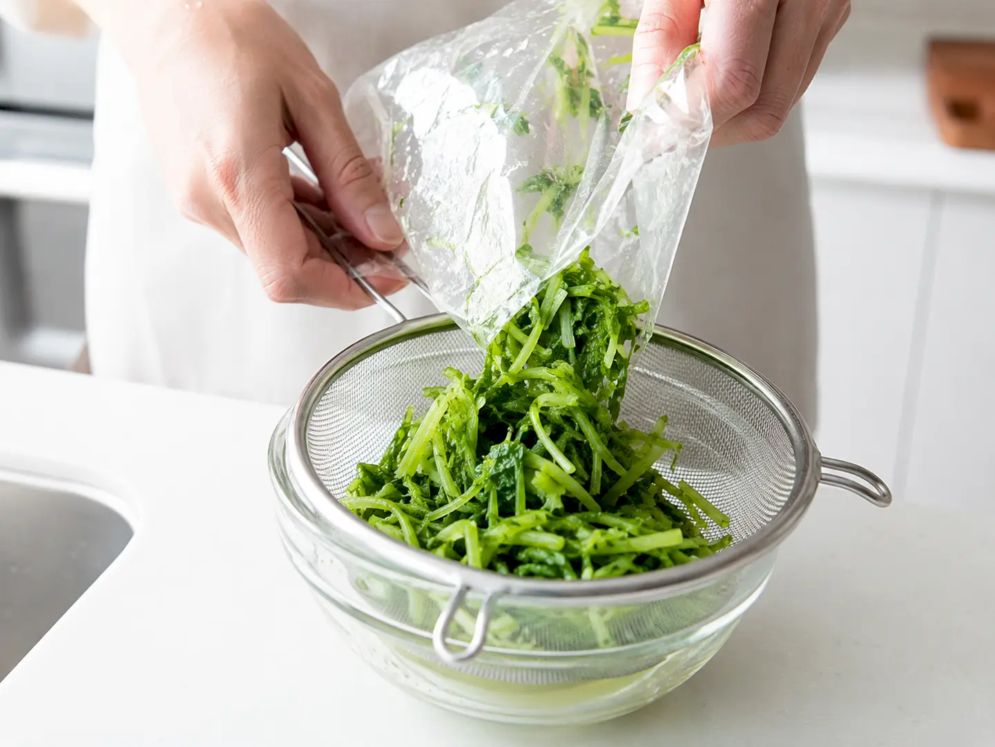 水菜漬けをざるへ移して余分な水気を軽く切っている工程