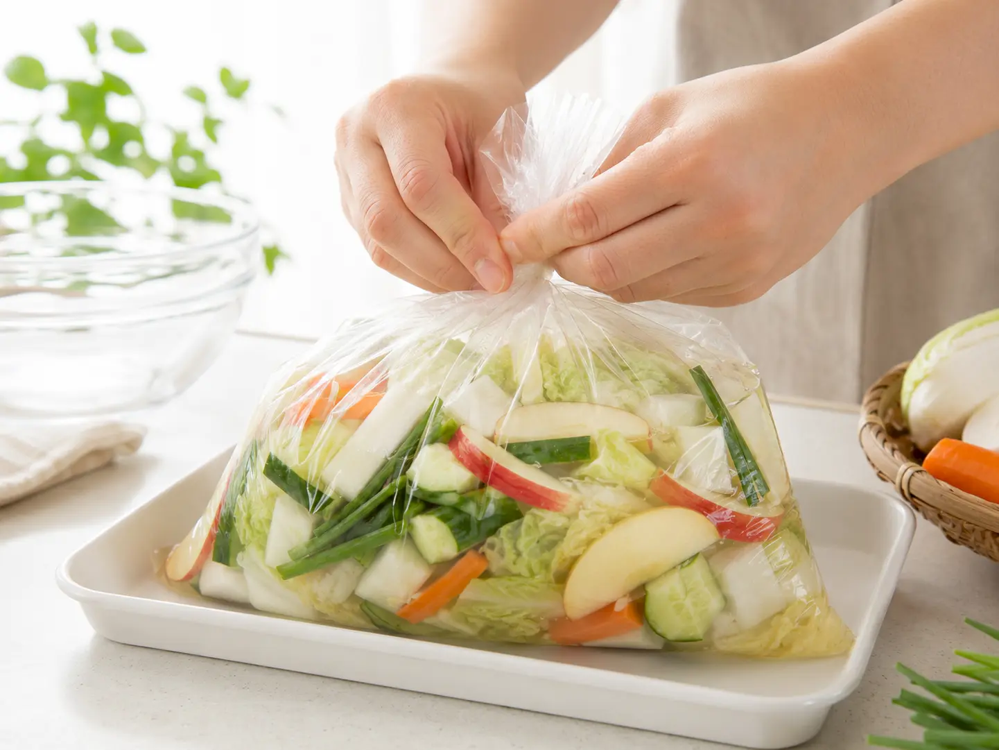 野菜と水キムチ液を入れた食品用ポリ袋の口をしっかり閉じている工程