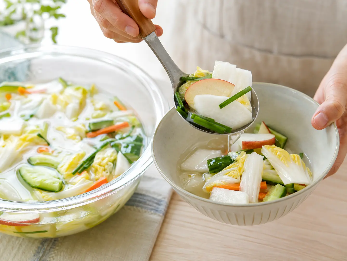水キムチの野菜と冷たい漬け汁を一緒に器へ盛り付けている工程