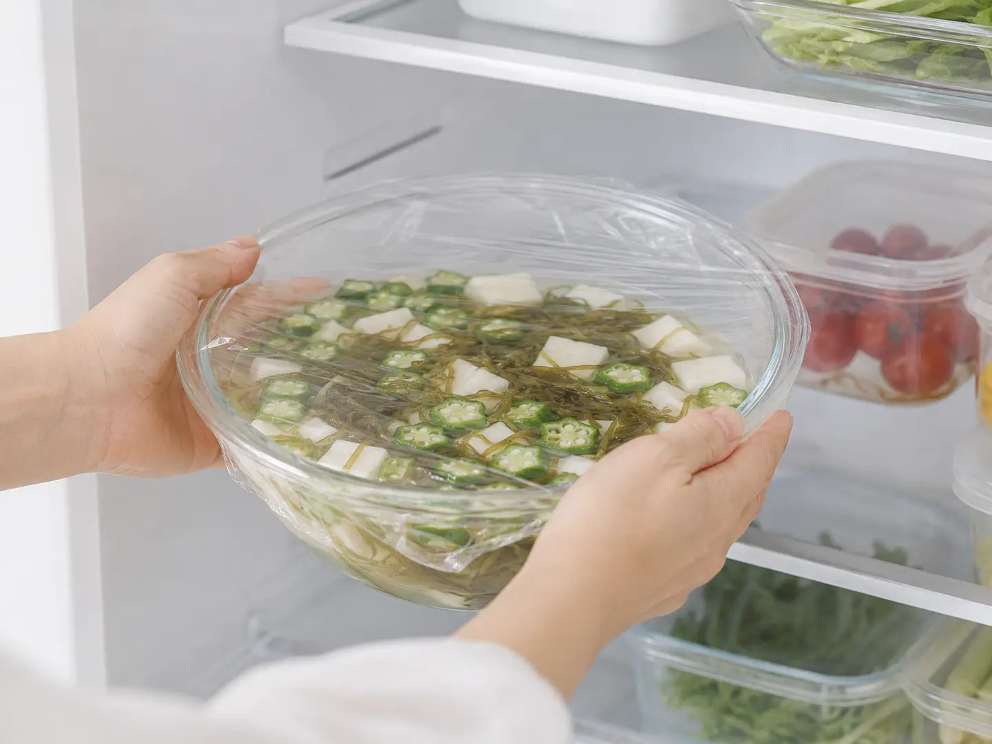 ラップをしたオクラと山芋の水キムチを家庭用冷蔵庫へ入れている工程