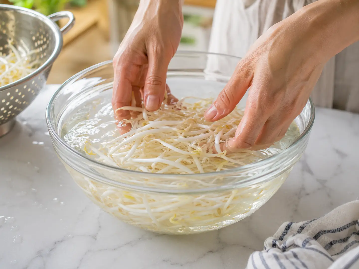 下ゆでしたもやしを清潔な冷水へ短時間取って冷ましている工程
