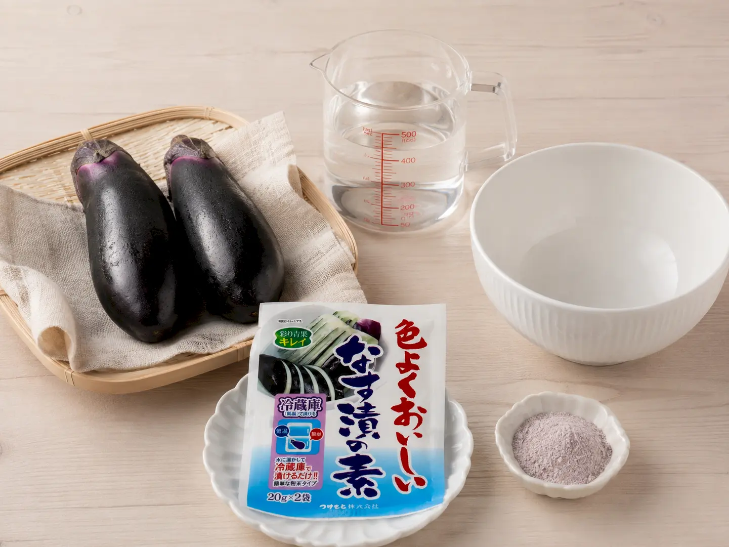 なす2本(約200g)、水200ml、色よくおいしいなす漬の素の銀色の小袋1袋(20g)、保存袋を並べた材料写真