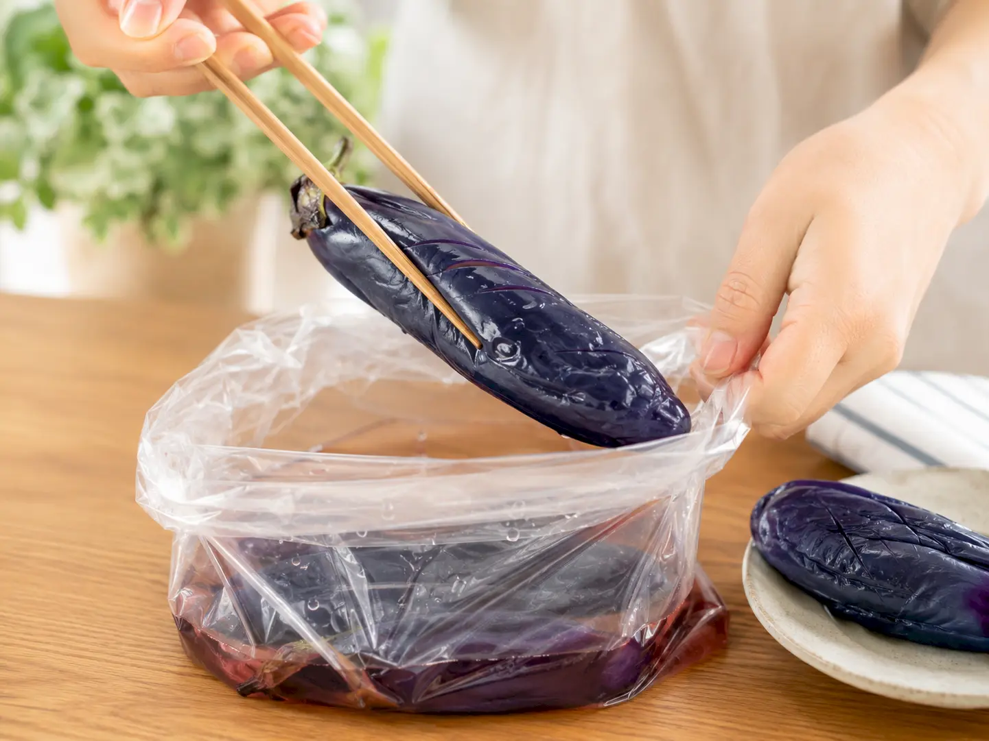 色よく漬かったなすを保存袋から清潔な箸で取り出している工程