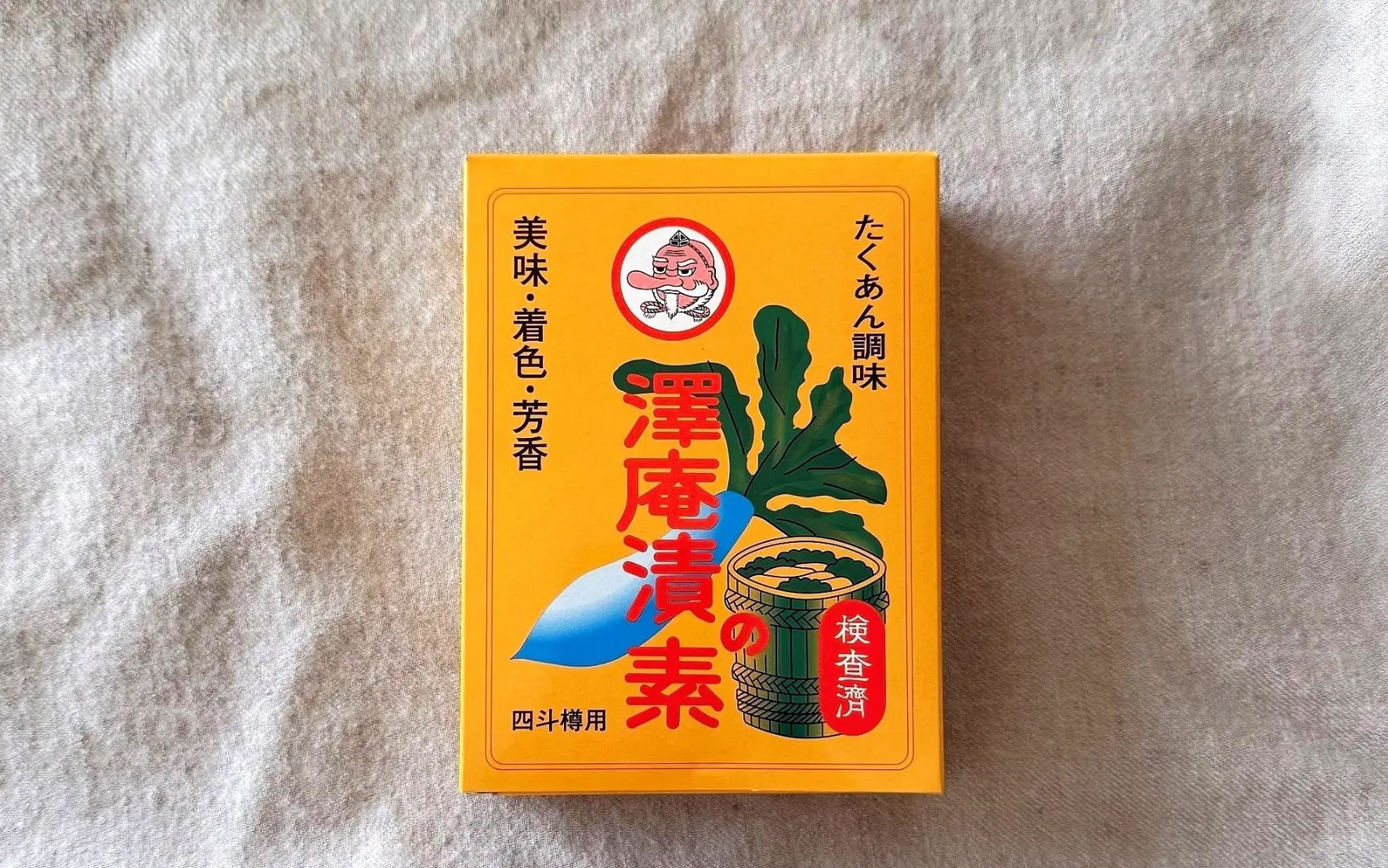 美味、着色、芳香と記載されたオレンジ色の澤庵漬の素4斗樽用80gの商品パッケージ