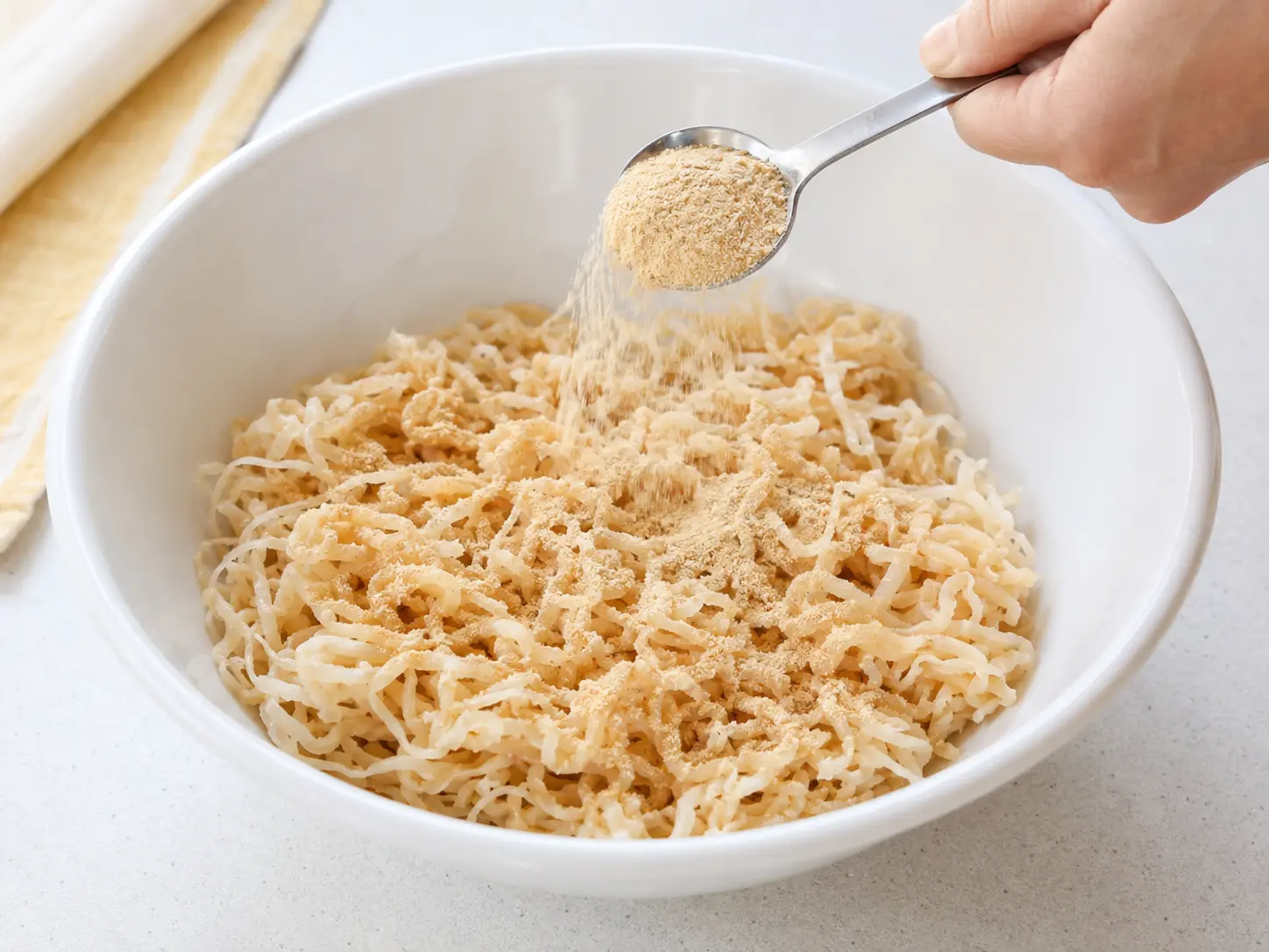 水気を絞った切り干し大根へ淡い色の粉末調味料を大さじ2杯加えている工程