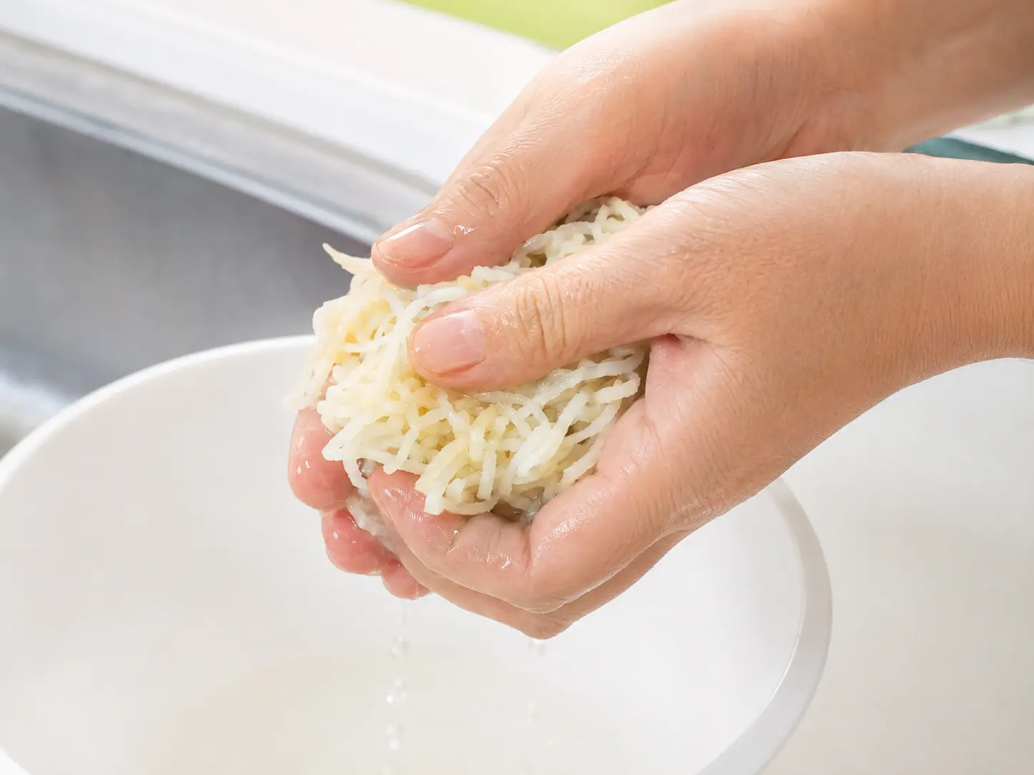 清潔な両手で戻した切り干し大根の水気をしっかり絞っている工程