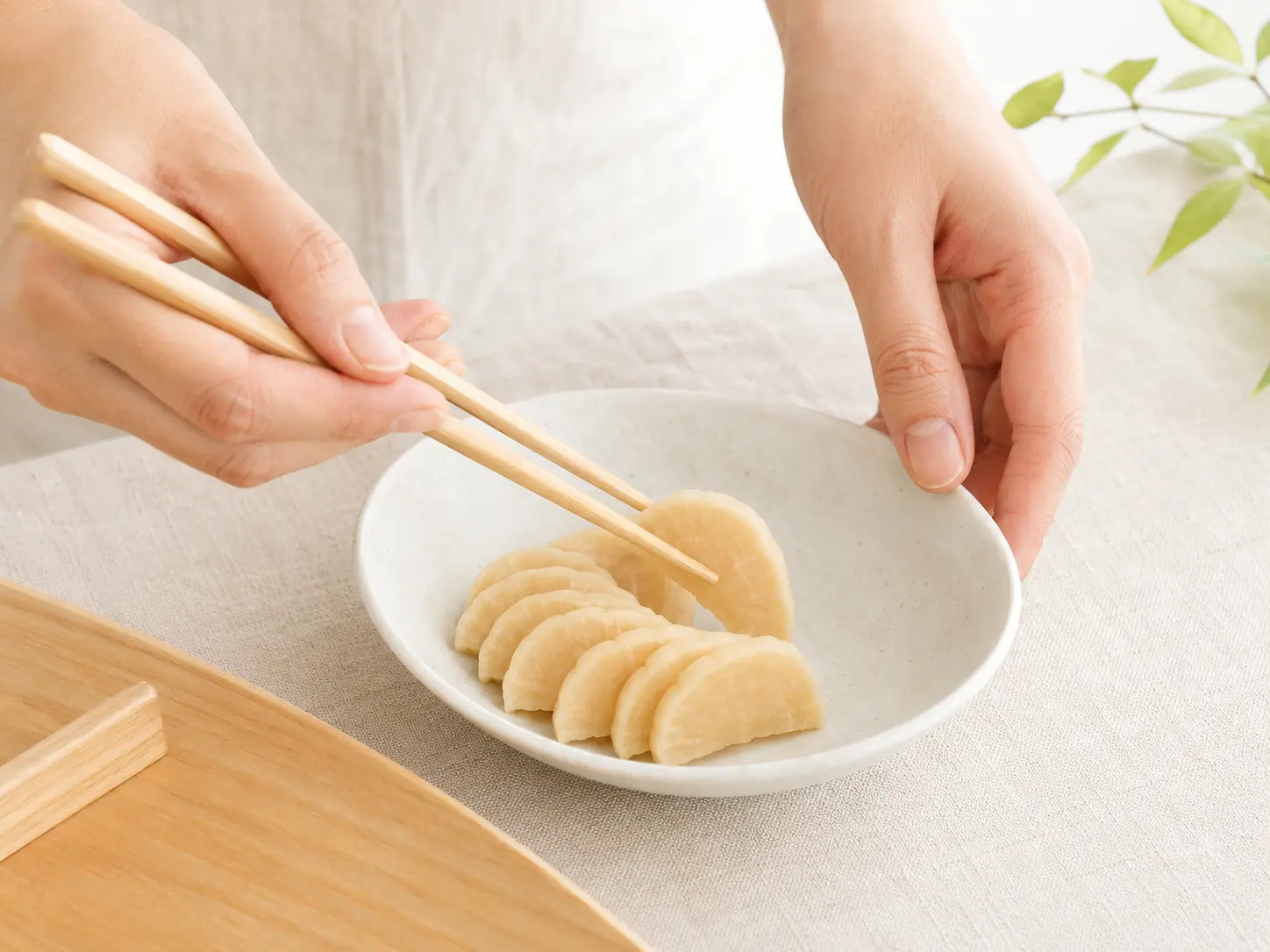 食べやすく切った甘口たくあんを白い小鉢へ盛り付ける手元