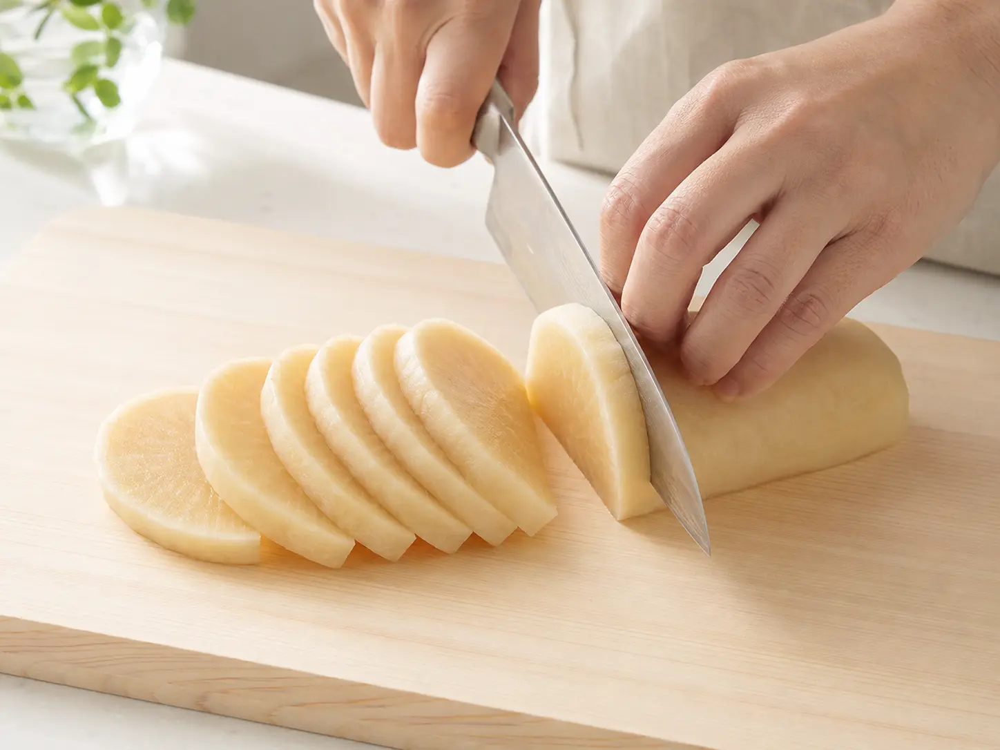 漬け上がった淡い色のたくあんを清潔な包丁で食べやすく切る手元
