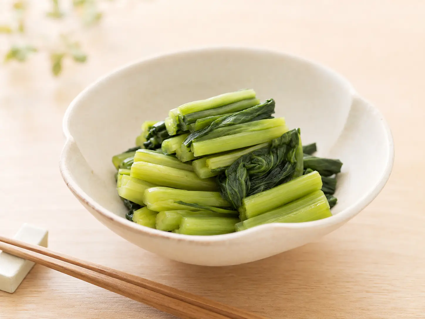 漬け上がった自然な緑色の野沢菜漬けを食べやすく切って生成りの器へ盛る手元