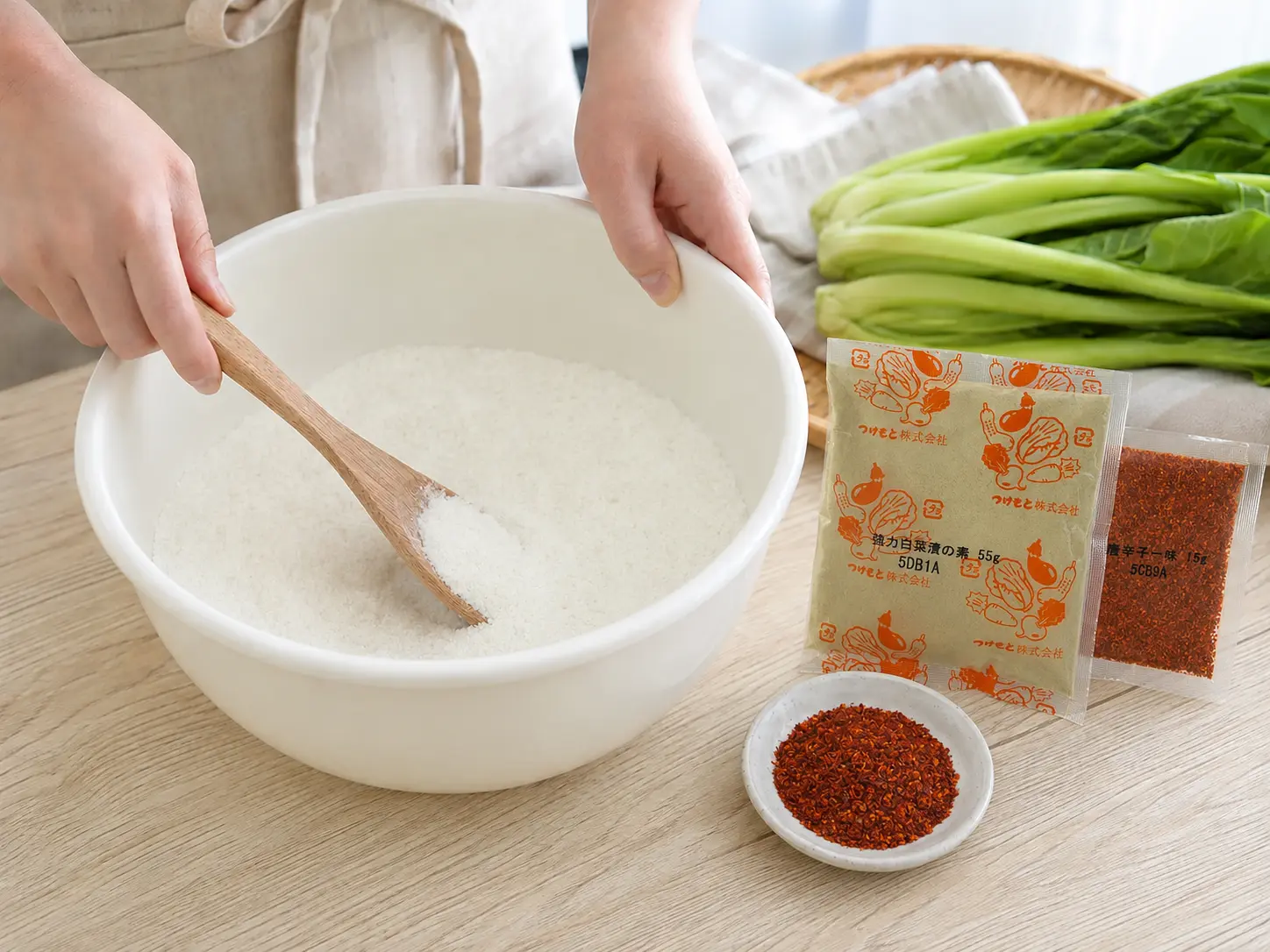 食塩600gと強力白菜漬の素の本品55gを清潔なボウルで混ぜる手元