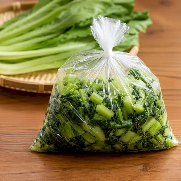 白菜漬の素をもみ込んだ野沢菜をポリ袋に入れて空気を抜いているイメージ
