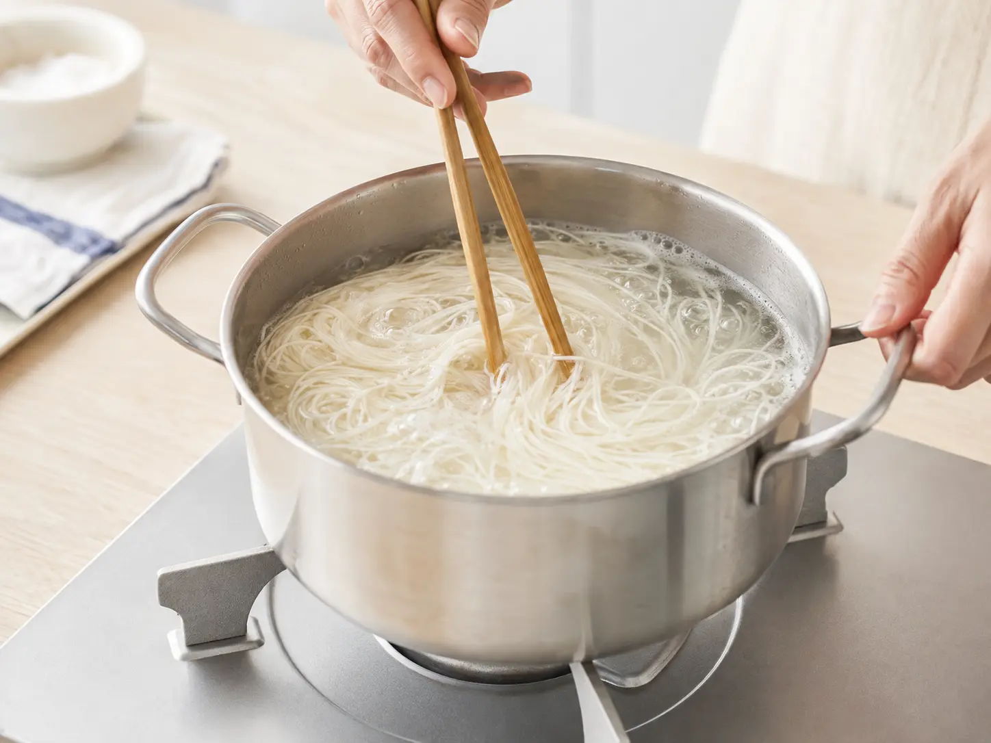 家庭用の鍋でそうめんを商品表示どおりにゆでている手元