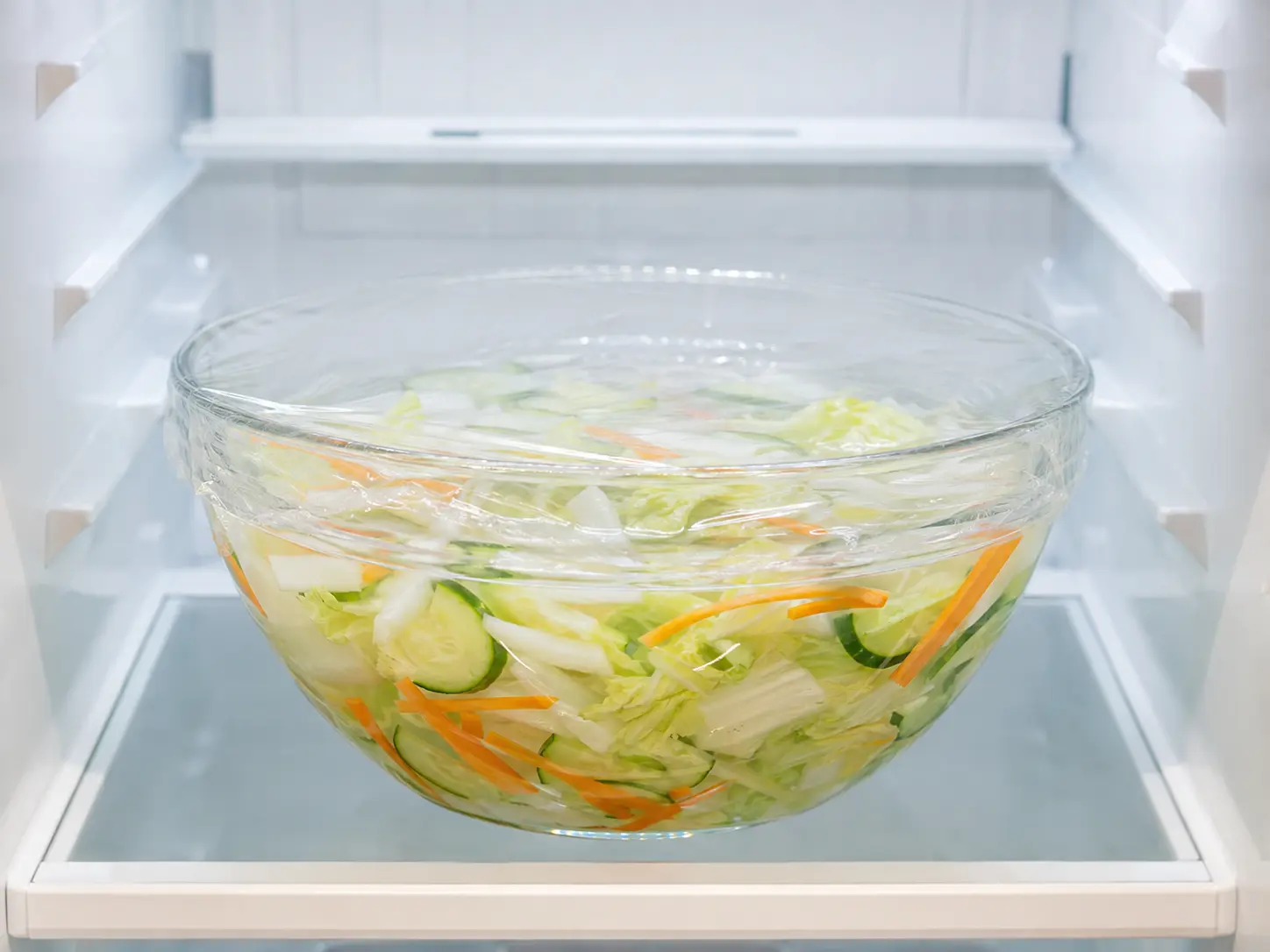 ラップをした透明なボウルに野菜入りの水キムチを入れ、冷蔵庫で冷やしている状態