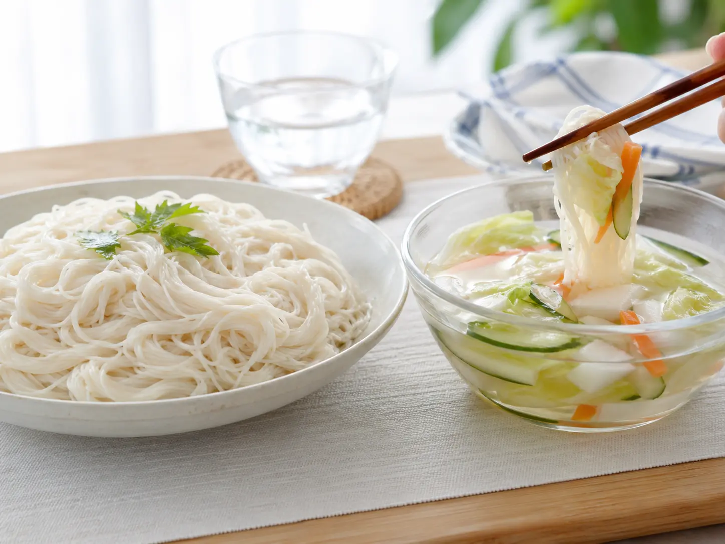 白い器の冷たいそうめんと、透明な器に盛った野菜入り水キムチのつけつゆ
