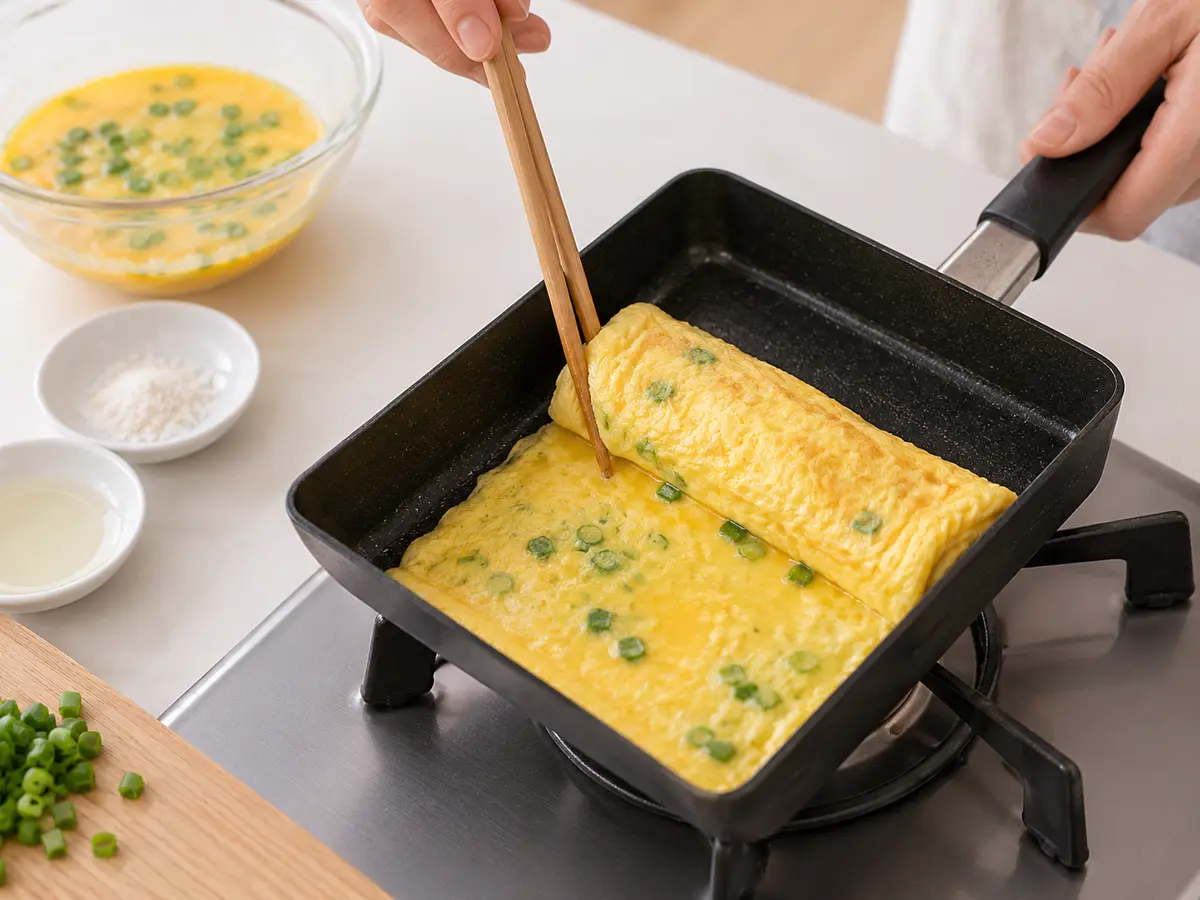 塩麹と刻みねぎを混ぜた卵を玉子焼き器で巻きながら焼く工程