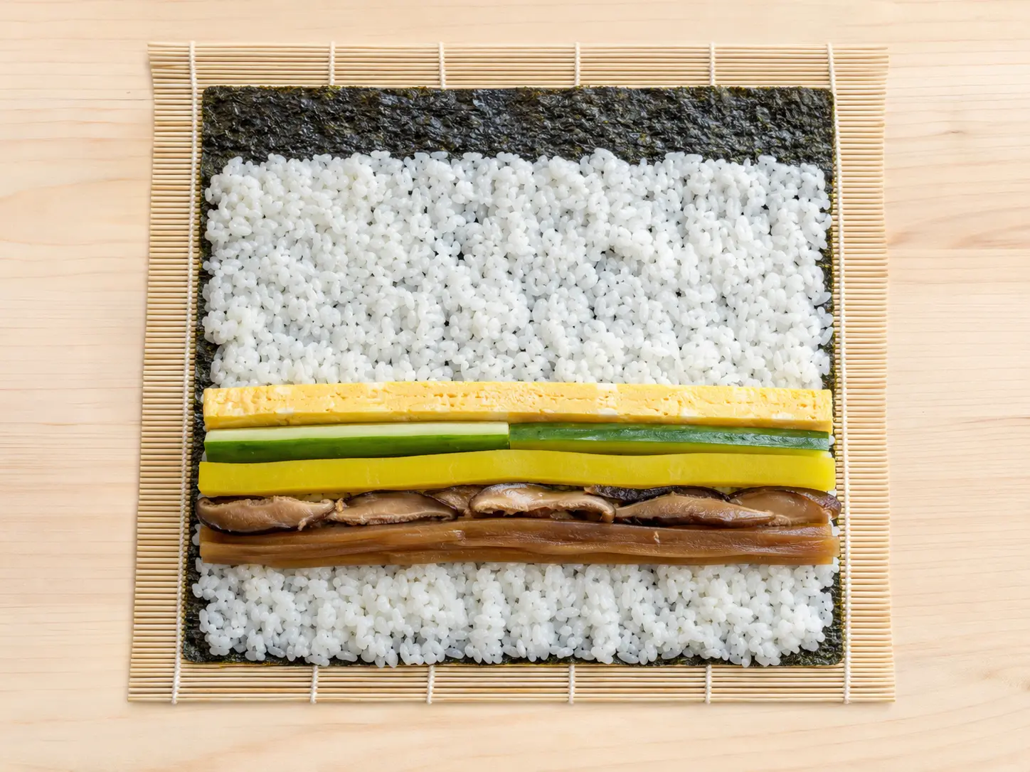 巻きすの上にのりとすし飯を広げ、太巻きの具を並べた様子